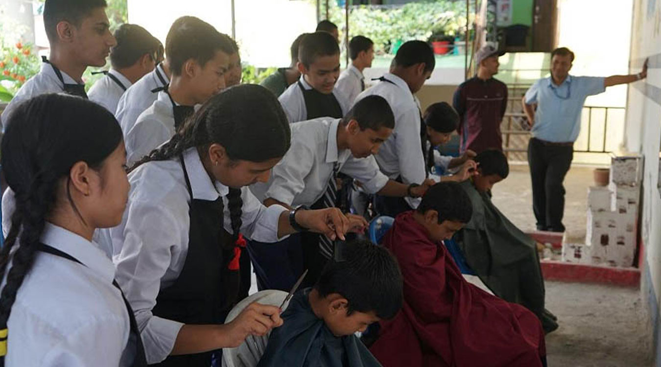 विद्यार्थीलाई सीप सिकाउन कपाल काट्ने तालिम दिइँदै